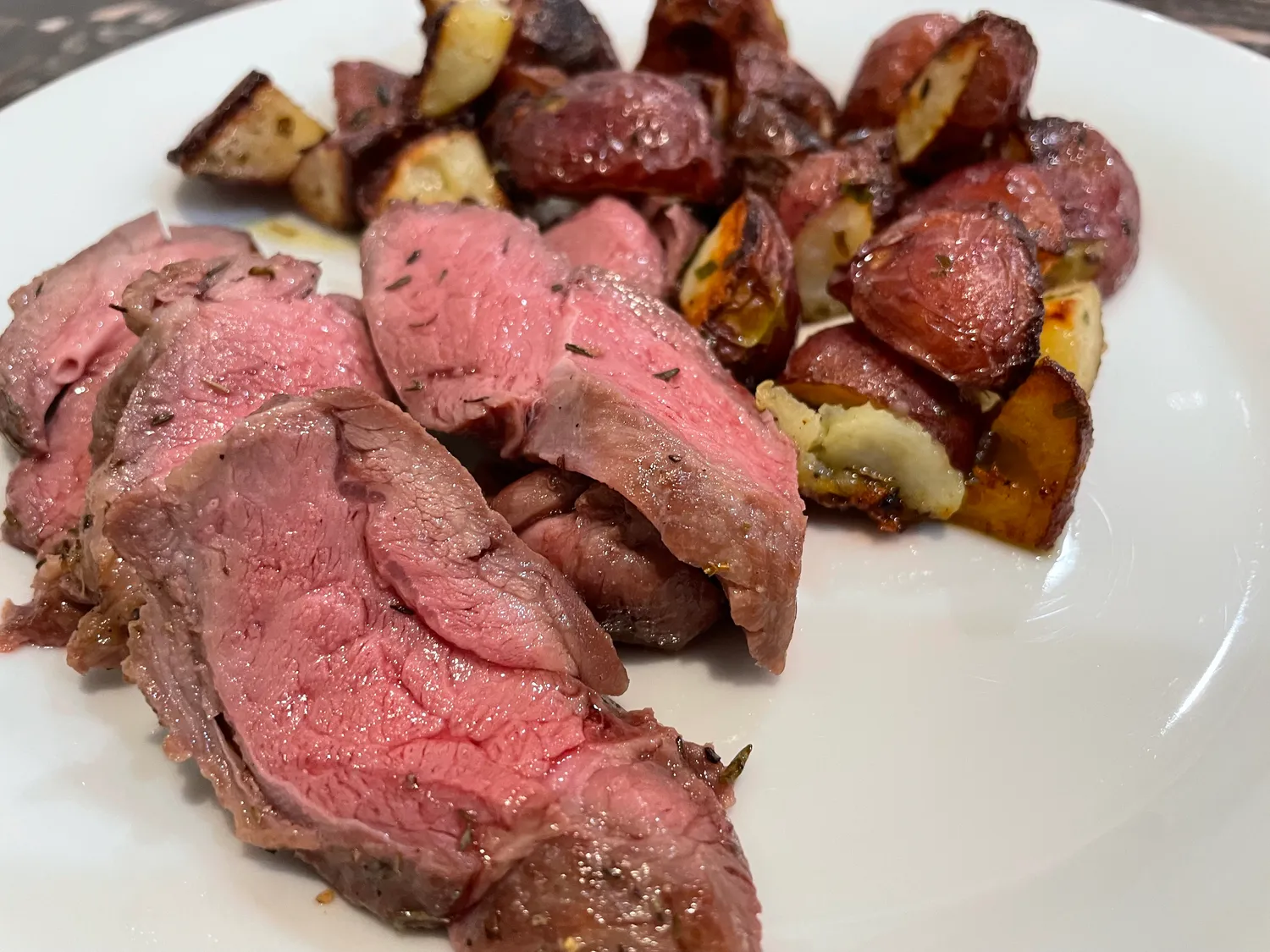 Sliced lamb with roasted potatoes.