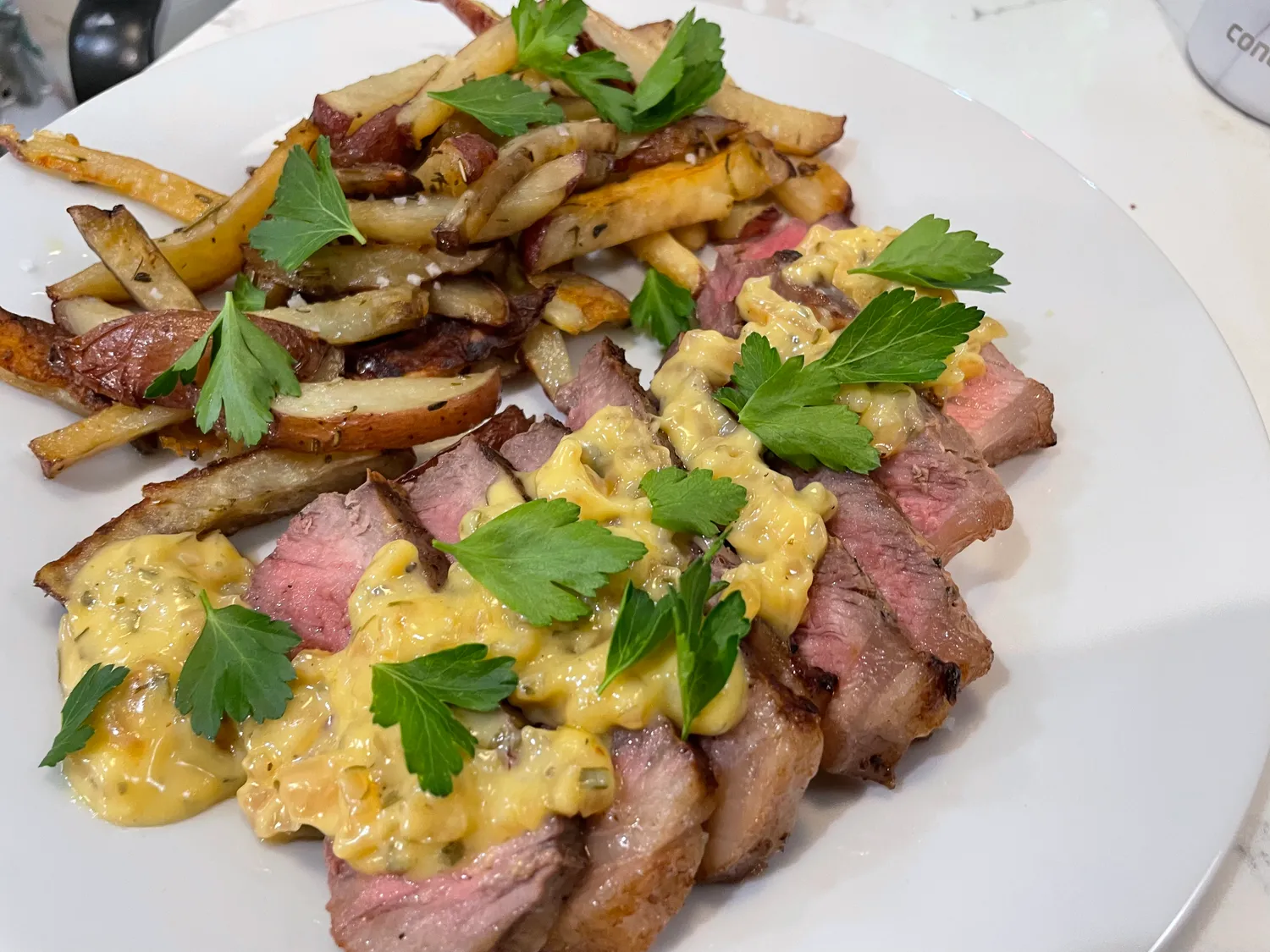 Sliced steak with a bright yellow sauce, salted 'frites' and a sprinkling of parsley.